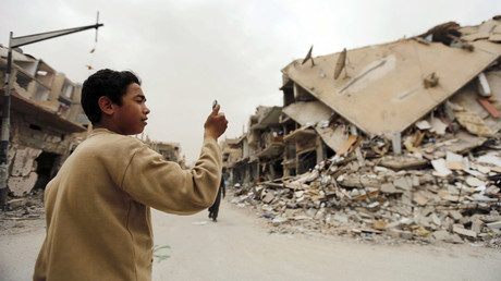 A boy takes a picture with his mobile phone of damaged buildings during his visit to the city of Palmyra, Syria April 9, 2016. © Omar Sanadiki