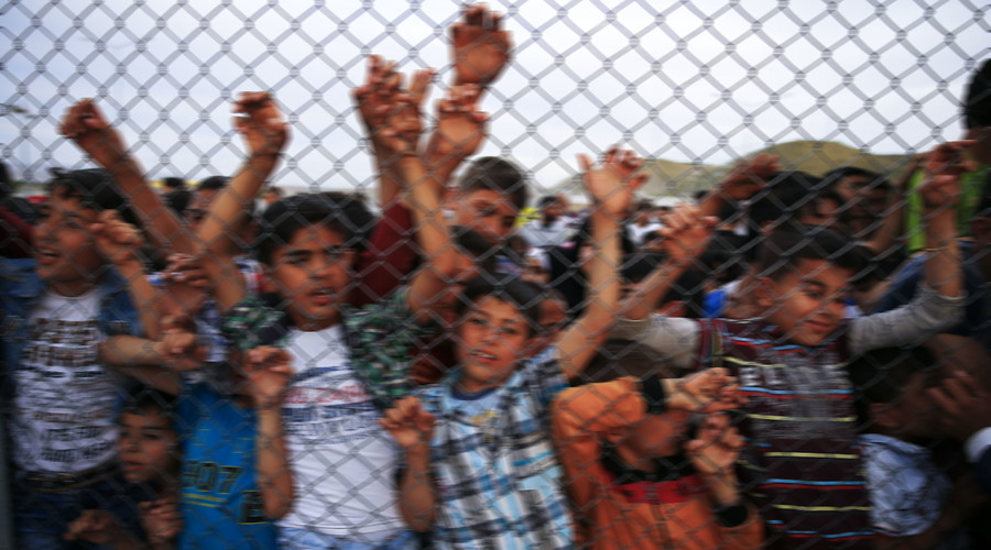Refugee youths gesture from behind a fence at Nizip refugee camp near Gaziantep, Turkey. © Umit Bektas
