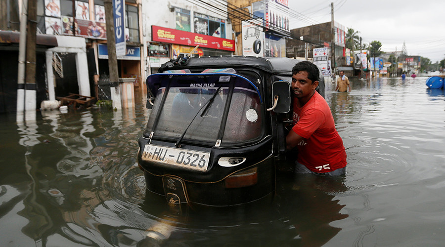 A man pushes his trishaw through a flooded road in Wellampitiya, Sri Lanka May 21, 2016 © Dinuka Liyanawatte