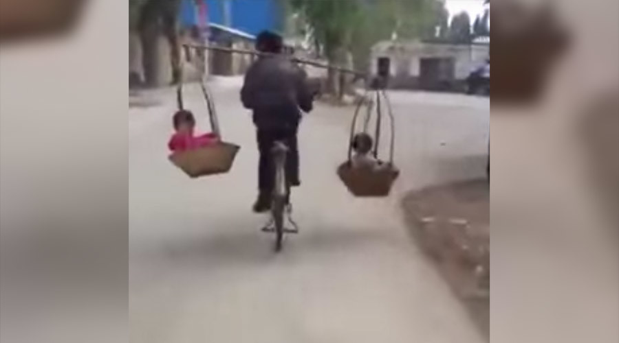 Dexterous dad carries children in baskets while balancing on bike (VIDEO)