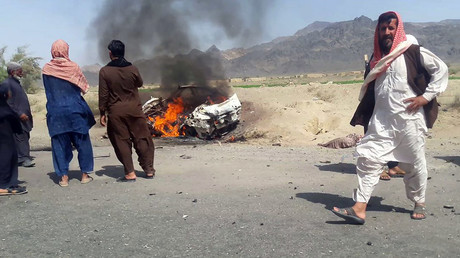 Pakistani local residents gathering around a destroyed vehicle hit by a drone strike in which Afghan Taliban Chief Mullah Akhtar Mansour was believed to be traveling © 