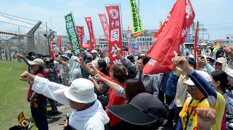 People raise their fists as they shout slogans to protest against the US military presence in front of the US Kadena Air Base in Cyatan, Okinawa prefecture, on May 21, 2016 © Jiji Press