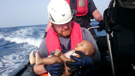 This handout photo released by German humanitarian NGO Sea-Watch shows a Sea-Watch crew member holding a drowned baby after a wooden boat transporting migrants capsized off the Libyan coast on May 27, 2016. © Christian Buttner 