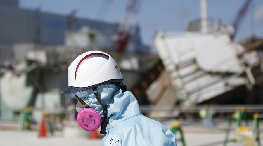 A Tokyo Electric Power Co. (TEPCO) employee, wearing a protective suit and a mask, walks in front of the No. 1 reactor building at TEPCO's tsunami-crippled Fukushima Daiichi nuclear power plant in Okuma town, Fukushima prefecture © Toru Hanai 