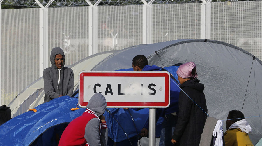 Migrants stand near a Calais city sign along a road near the makeshift camp called "The New Jungle" in Calais, France © Regis Duvignau 
