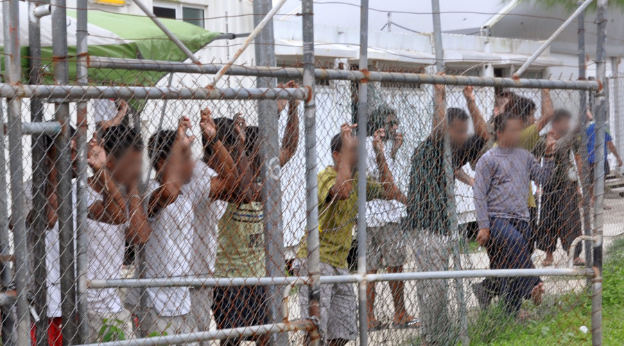 Asylum-seekers look through a fence at the Manus Island detention centre in Papua New Guinea © Eoin Blackwell
