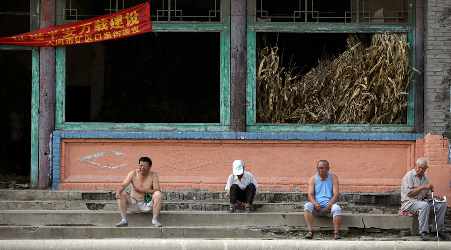 Villagers sit on stairs outside an abandoned old theatre building in an area where land is sinking near a coal mine in Kouquan township of Datong, China's Shanxi province, August 1, 2016. © Jason Lee