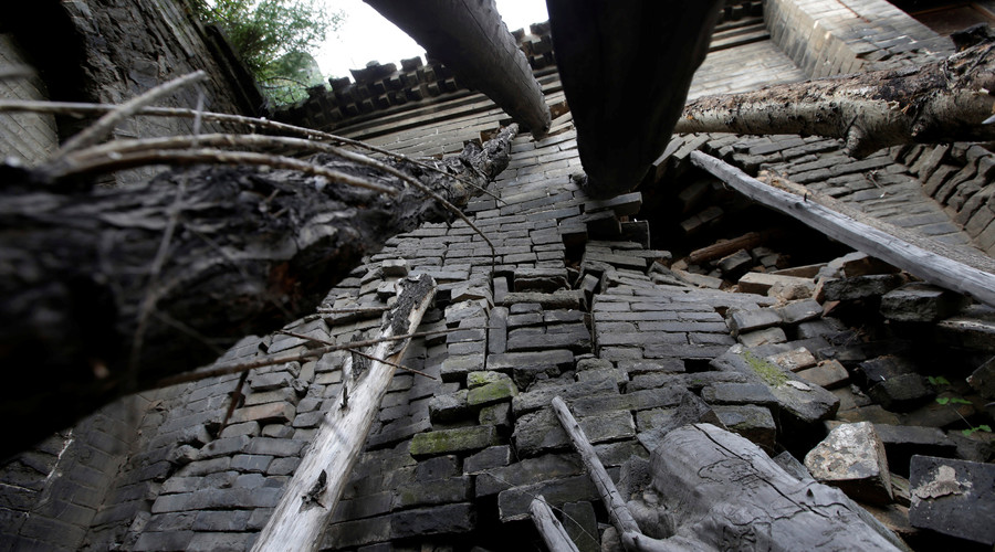 Tree trunks are set up to support a leaning wall of Li Yonghua's damaged cave house in an area where land is sinking next to a coal mine, in Helin village of Xiaoyi, China's Shanxi province, August 2, 2016. © Jason Lee