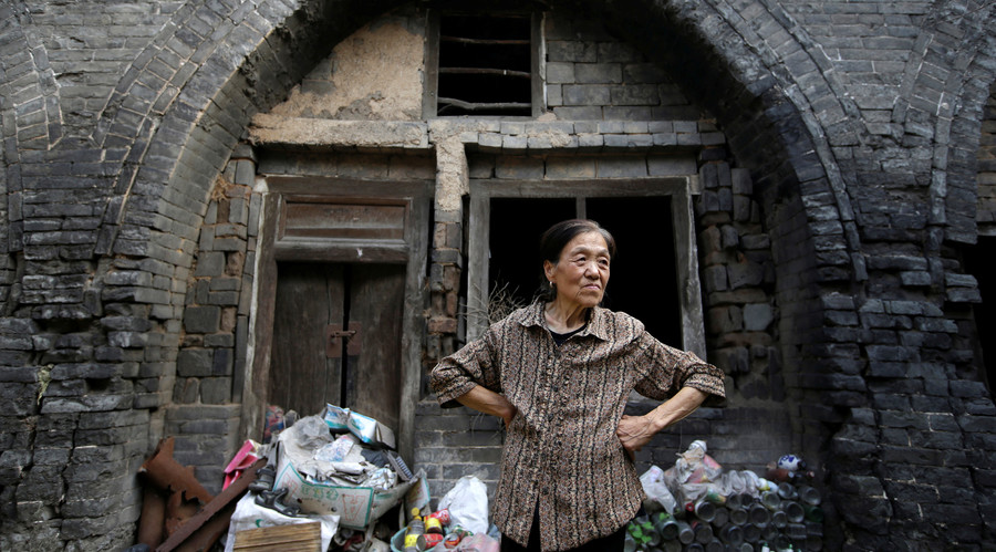 Li Yonghua, 65, stands in front of her damaged cave house in an area where land is sinking next to a coal mine, in Helin village of Xiaoyi, China's Shanxi province, August 2, 2016. © Jason Lee