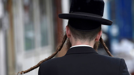 An orthodox Jewish man walks through a street in Stamford Hill north London, Britain. © Hannah McKay