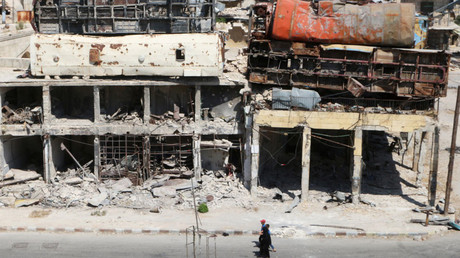 People walk past damaged buses positioned atop a building as barricades in the rebel-held Bab al-Hadid neighbourhood of Aleppo, Syria August 18, 2016. © Abdalrhman Ismail 