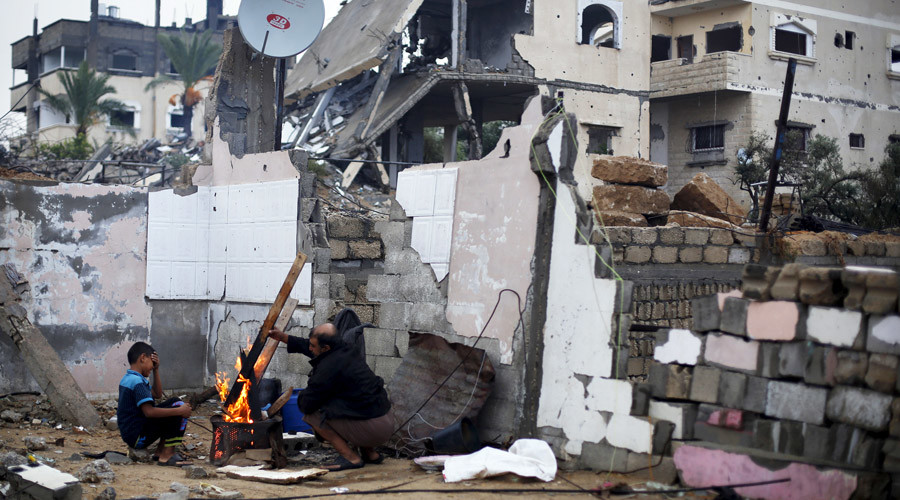 Palestinians use wood to light a fire inside the ruins of their house, that witnesses said was destroyed by Israeli shelling during a 50-day war in the summer of 2014, on a rainy day in Gaza city © Suhaib Salem 