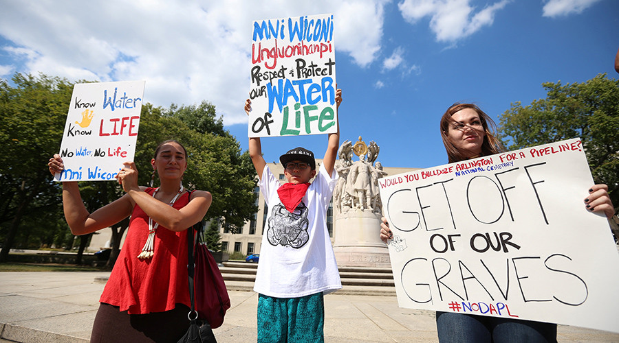 Protesters hold signs outside the U.S. District Court in Washington, where a hearing was being held to decide whether to halt construction of an oil pipeline in parts of North Dakota where a Native American tribe says it has ancient burial and prayer sites, September 6, 2016. Â© Kevin Lamarque
