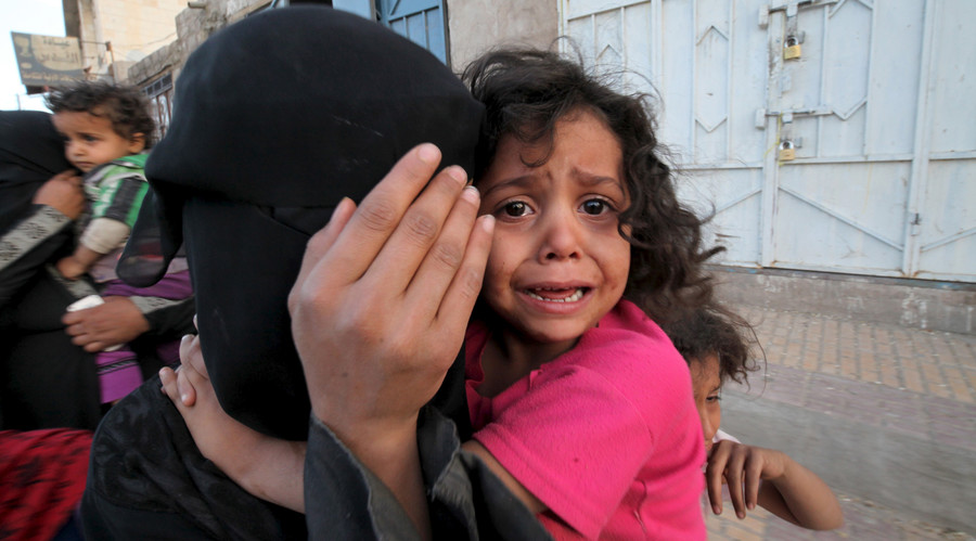 A girl cries next to her mother covering her face as they flee from an airstrike on an army weapons depot in Yemen's capital Sanaa. File photo. © Mohamed al-Sayaghi