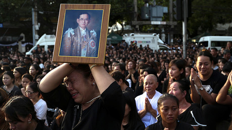 A woman cries while holding up a portrait of Thailand's King Bhumibol Adulyadej while his body is being moved from the Bangkok hospital where he died to the Grand Palace, in Bangkok, Thailand © Athit Perawongmetha