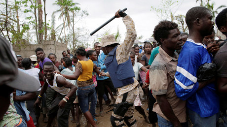 A Haitian national police officer keeps people away during distribution of supplies after Hurricane Matthew in Torbeck, Haiti, October 19, 2016. © Andres Martinez Casares 