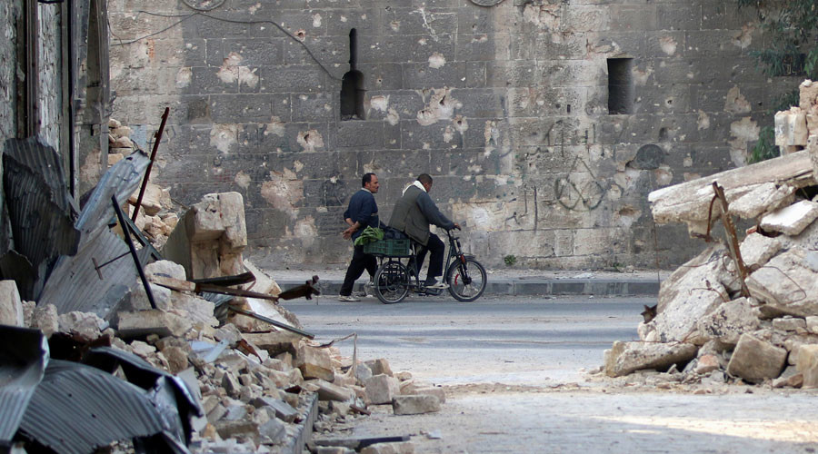 A man walks past a man riding a bicycle near the rubble of damaged buildings in the rebel held area of Old Aleppo, Syria November 14, 2016. © Abdalrhman Ismail