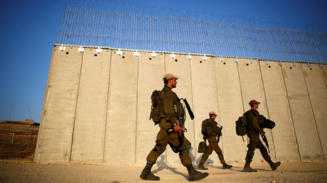 Soldiers walk past the ongoing construction site of Israel's barrier with the West Bank as seen from Havat Ela in southern Israel. © Amir Cohen