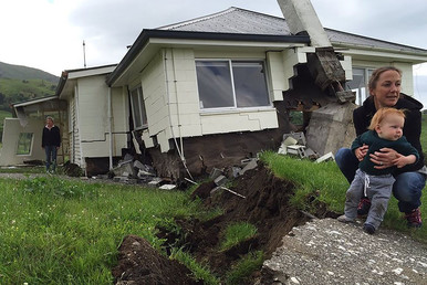 A woman and child are in front of a house damaged by an earthquake as it sits on the fault line at Bluff Station near Kaikoura on the South Island's east coast. © Alex Perrottet / Radio New Zealand