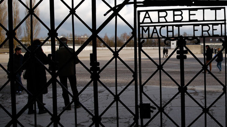 Visitors walk past the main gate with the sign 