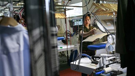 A worker presses clothing at a dry cleaner, San Francisco, California. © Robert Galbraith