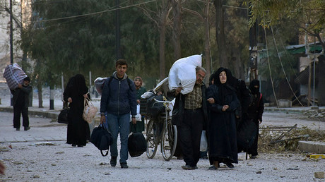 People, who evacuated the eastern districts of Aleppo, carry their belongings as they arrive in a government held area of Aleppo, Syria, in this handout picture provided by SANA on December 7, 2016. © SANA