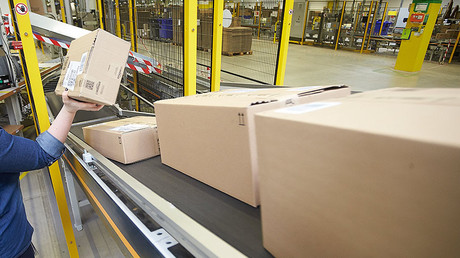 An employee of the Amazon logistics centre places a parcel on a conveyor belt. © Thomas Frey