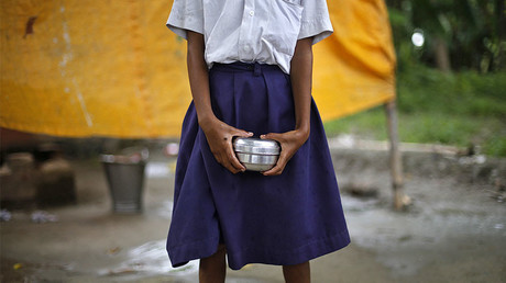 FILE PHOTO: A school girl holds a container to receive her free mid-day meal, at primary school, India. © Adnan Abidi 