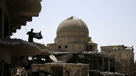 A member of Iraqi security forces holds a flag of Islamic State militants on the top of a destroyed building from clashes in the Old City of Mosul, Iraq July 10, 2017 © Thaier Al-Sudani 