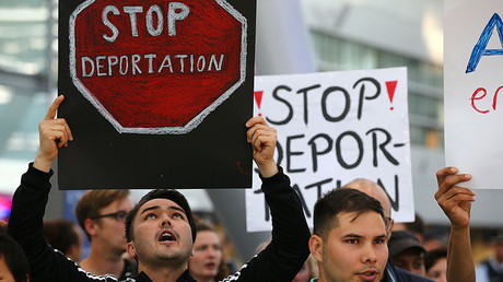 People hold signs as they protest against the German government's decision to deport migrants who were denied asylum, at Duesseldorf Airport, Germany September 12, 2017. © Wolfgang Rattay