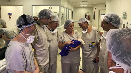 Medical staff holding the first baby to be born from dead woman's womb. © Reuters 