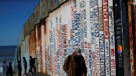 Migrants walk next to the border wall in Tijuana, Mexico, December 7, 2018. © Reuters / Carlos Garcia Rawlins 