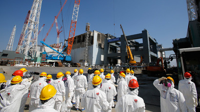 Members of the media wearing protective suits and masks being escorted by Tokyo Electric Power Co (TEPCO) employees as they visit near the No.4 reactor (C) and the construction of a foundation (R) for storage of melted fuel rods at TEPCO's tsunami-crippled Fukushima Dai-ichi nuclear power plant in the town of Okuma, Fukushima prefecture (AFP Photo / Pool / Issei Kato)
