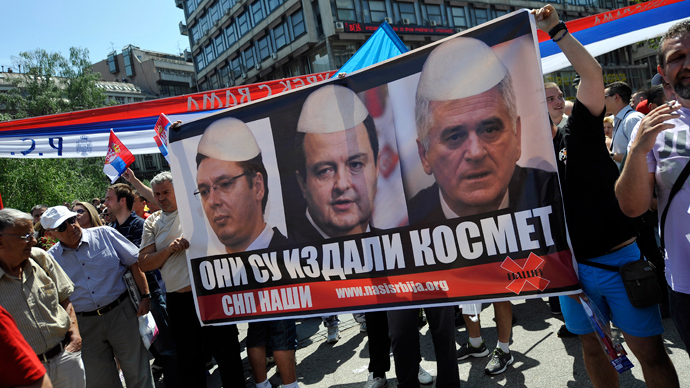 Demonstrators hold a poster showing mock images of Serbian top officials wearing traditional Albanian hats during a protest against the accord on the normalisation of relations between Serbia and Kosovo in the Serbian capital Belgrade on May 10, 2013 (AFP Photo / Andrey Isakovic)
