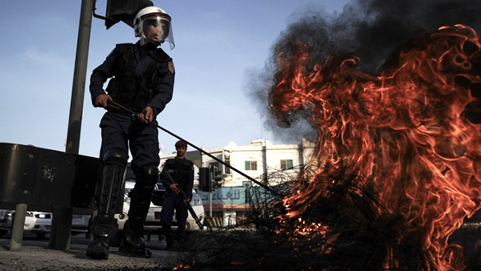 A Bahraini policeman extinguishes tyres burning during clashes with riot police following a protest in solidarity with jailed Bahraini women in the village of Jidhafs, west of Manama, on June 13, 2013. (AFP Photo / Mohammed Al-Shaikh)