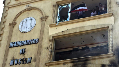 Egyptian protesters wave their national flag as they stand in the burnt headquarters of the Muslim Brotherhood in Cairo on July 1, 2013 (AFP Photo / Khaled Desouki)