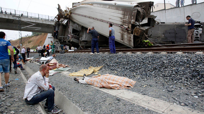 A wounded victim sits next to a body covered with a blanket after a train crashed near Santiago de Compostela, northwestern Spain, July 24, 2013 (Reuters / La Voz de Galicia)