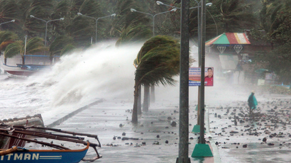 A resident (R) walks past high waves pounding the sea wall amidst strong winds as Typhoon Haiyan hit the city of Legaspi, Albay province, south of Manila on November 8, 2013. (AFP Photo / Charism Sayat) 