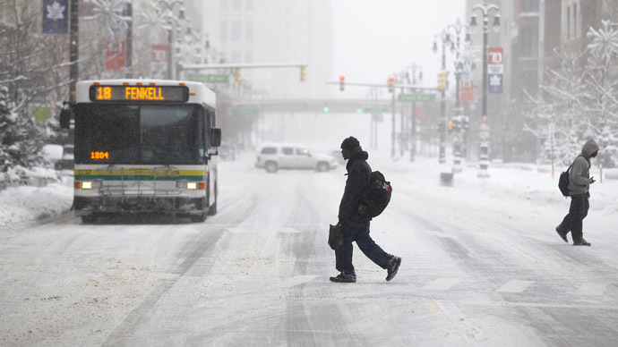 Pedestrians cross Woodward Avenue as it snows as the area deals with record breaking freezing weather January 6, 2014 in Detroit, Michigan. (Joshua Lott/Getty Images/AFP)