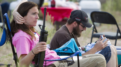 Chris Shelton of Las Vegas interacts with his 1-week-old son as his mother Shelley Shelton holds his rifle during a Bundy family "Patriot Party" near Bunkerville, Nevada, April 18, 2014. (Reuters/Steve Marcus)