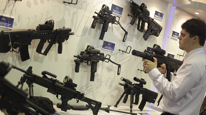 A man looks at a sub machine gun displayed at the Latin America Aero and Defence trade show (Reuters / Ricardo Moraes)