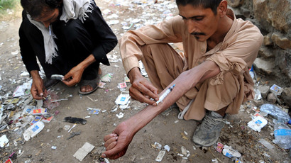 An Afghan addict smokes heroin while another addict injects heroin in the city of Jalalabad (AFP Photo / Noorullah Shirzada)