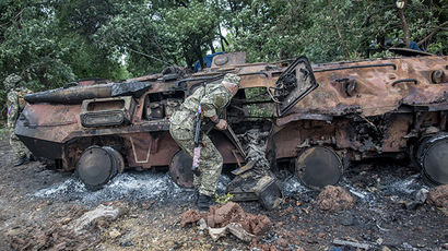 A self-defense member inspects a burnt Ukrainian armored personnel carrier near Slavyansk on June 27, 2014. (RIA Novosti / Andrey Stenin)