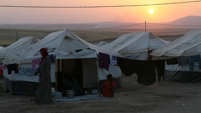 An Iraqi displaced woman walks at sunset past a tent provided by the UN refugee agency at a temporary camp set up to shelter people fleeing violence in northern Iraq on June 27, 2014 in Aski kalak, 40 kms west of the Kurdish autonomous region's capital Arbil. (AFP Photo / Karim Sahib)