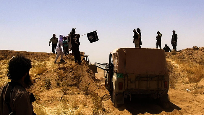 File image: Islamic State of Iraq and the Levant (ISIL) militants waving the trademark Jihadits flag as vehicles drive on a newly cut road through the Syrian-Iraqi border between the Iraqi Nineveh province and the Syrian town of Al-Hasakah (AFP Photo)