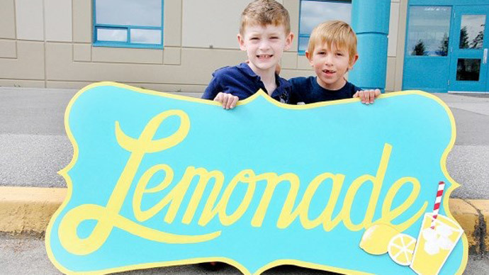 Quinn Callender (L) and Brayden Grozdanich (R) pose by their lemonade stand outside a grocery store in Pitt Meadows, B.C. Photo from youcaring.com