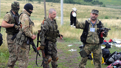 A member of the  self-defense forces holds up a stuffed animal as others look on at the site of the crash of a Malaysian airliner carrying 298 people from Amsterdam to Kuala Lumpur in Grabove, in east Ukraine, on July 18, 2014. (AFP Photo / Dominique Faget)
