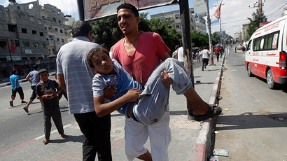 A Palestinian man carries an injured child following an Israeli military strike on a UN school in Rafah, in the southern Gaza Strip on August 3, 2014 (AFP Photo / Said Khatib)