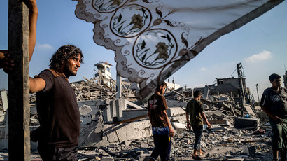 Palestinians stand next to a makeshift shelter erected outside their 