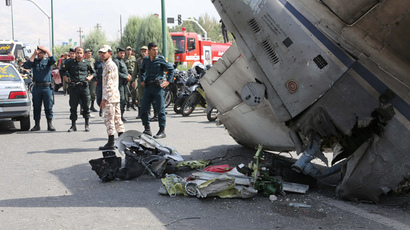 Iranian Revolutionary Guards and security forces stand next to the remains of a plane as they secure the scene of a crash near Tehran's Mehrabad airport on August 10, 2014. (AFP Photo / Atta Kenare)